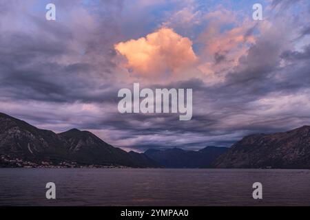 Wolken über der Bucht von Kotor bei Sonnenaufgang, mit wechselnden Wolkenformen und Farbverläufen am Himmel, die sich auf der Wasseroberfläche spiegeln und einen Spiegel-ef erzeugen Stockfoto