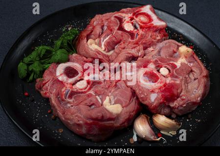 Rohes Steak, Kalbhals auf den Knochen, frisches Fleisch, auf einem schwarzen Teller, Blick von oben, keine Leute Stockfoto