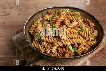 Pasta in der Marine, Pasta mit Hackfleisch, Teller auf einem Holztisch, hausgemachte Fusilli Nudeln, ohne Leute Stockfoto