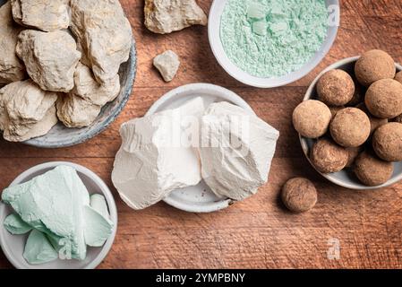 Essbare Karamell- und grüne Tonsteine, Tonsteine und Pulver auf Holztisch aus nächster Nähe. Natürliche essbare Kalziumkreide und Kaolin-Tonkugeln zum Essen. Stockfoto