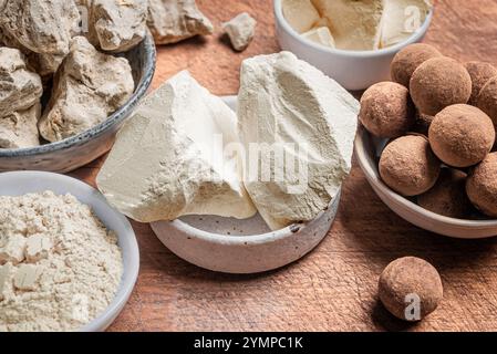 Essbare Karamell-Tonsteine, Tonsteine und Pulver auf Holztisch aus nächster Nähe. Natürliche essbare Kalziumkreide und Tonkugeln zum Essen. Stockfoto