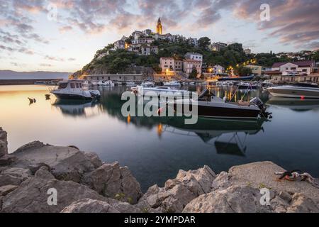 Hafen und Strand mit einem alten Dorf auf einem Hügel. Boote spiegeln sich im Wasser, die Sonne geht am adriatischen Horizont auf. Wunderschöne Landschaft, aufgenommen von hier Stockfoto