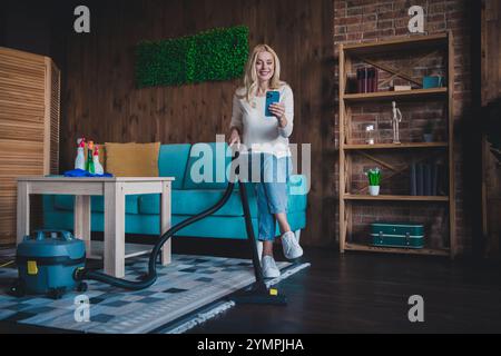 Foto von positiver guter Laune Frau gekleidetes weißes Hemd, das Hausarbeit macht, moderne Gadget im Haus-Appartementzimmer schickt Stockfoto
