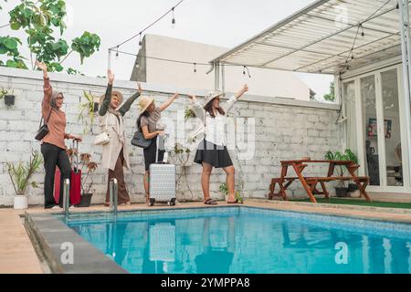 Freunde feiern fröhlich am Pool und posieren mit Gepäck während des Urlaubs Stockfoto