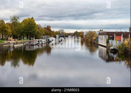 Häuser, verlassene Industrie und Boote reflektieren im westlichen Marktkanal in Amsterdam, Niederlande, 15. November 2024 Stockfoto