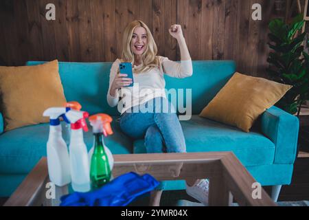 Foto von glänzenden Glücksfrau gekleidetes weißes Hemd, das Wochenende reinigt, Online-Shopping, modernes Gadget im Haus Apartment Zimmer Stockfoto