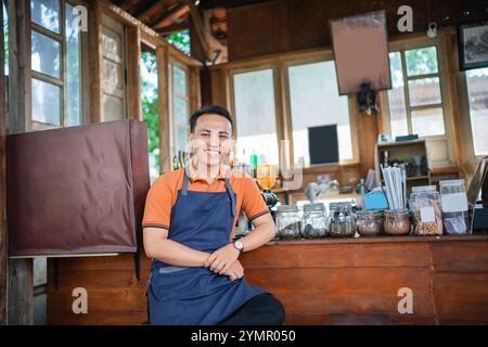 asiatischer gutaussehender Barista, der im Café sitzt Stockfoto