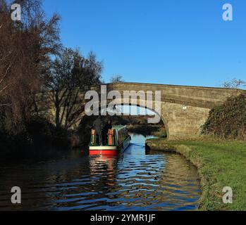 An einem sonnigen, aber kühlen Herbstnachmittag im November 2024 fährt ein schmales Boot unter der aus Stein gebauten Brücke, Prescott’s Bridge bei Rufford. Stockfoto