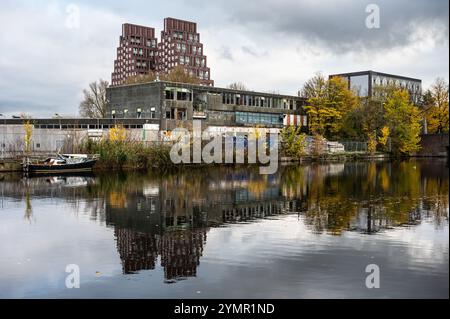 Häuser, verlassene Industrie und Boote reflektieren im westlichen Marktkanal in Amsterdam, Niederlande, 15. November 2024 Stockfoto