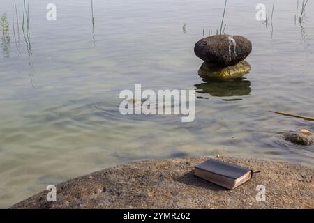 3. Mai 2018 Eine Bibel vor Felsen, die sich in flachen, ruhigen Untiefen des Galiläa-Meeres Israel an einem heißen, trüben Nachmittag stapeln Stockfoto