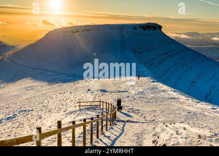 Wanderer auf einem schneebedeckten Gipfel des Pen-y-Fan nahe Sonnenuntergang Stockfoto