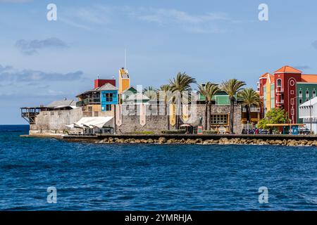 Das Rif Fort liegt am John F. Kennedy Boulevard in Willemstad, Curaçao, hier gesehen von Sint Annabaai. Das 1828 erbaute Küstenfort wurde in einen Einkaufs- und Essenskomplex mit einem Innenhof umgewandelt. Im Hintergrund rechts sind die pastellfarbenen Fassaden des Punda-Viertels zu sehen, einem UNESCO-Weltkulturerbe. Stockfoto