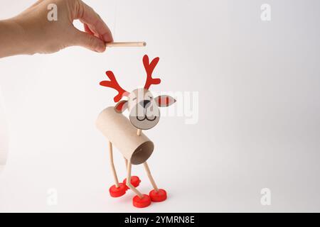 DIY-Rentierpuppe aus Pappröhrchen, roten Kunststoffkappen und Papier. Weißer Hintergrund. Weihnachtsbasteln und Dekorationskonzept. Kreatives fest Stockfoto