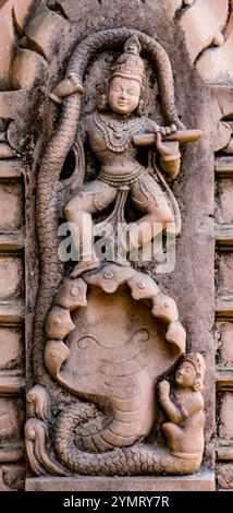 Antike Reliefschnitzerei aus Stein, die krishna zeigt, wie sie auf Kaliya, einer mythologischen mehrköpfigen Schlange, die Flöte spielt Stockfoto
