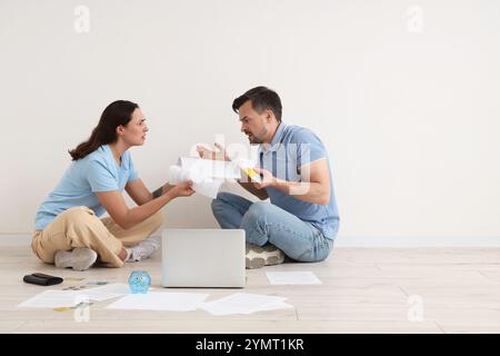 Depressives junges Paar, das auf dem Boden sitzt und zu Hause über Schulden streitet. Insolvenzkonzept Stockfoto