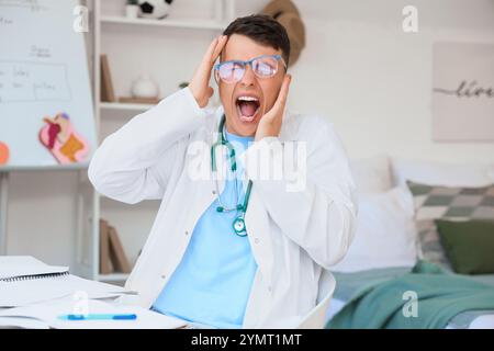 Gestresster männlicher Medizinstudent in Brille zu Hause Stockfoto