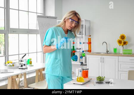 Wissenschaftlerin mit Probenkolben, Sonnenblumensamen und Sprossen im Labor Stockfoto