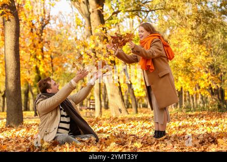 Wunderschönes, liebevolles junges glückliches Paar, das Herbstlaub im Herbstpark wirft Stockfoto
