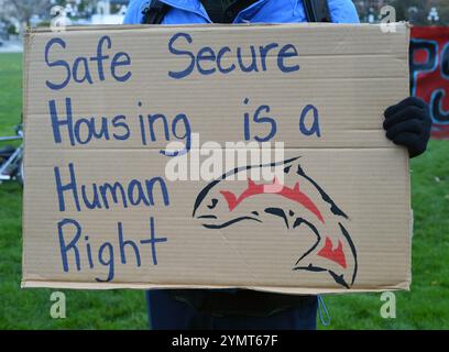 Victoria, British Columbia, Kanada, 22. November 2024 - Ein Demonstrant hält ein Schild auf einer Demonstration gegen die hohen Wohnkosten und die Notlage der Obdachlosen vor dem Parlamentsgebäude in Victoria, BC, Kanada. Don Denton/Alamy Live News Stockfoto