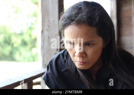 Ein Nahporträt einer Frau mit tiefer Konzentration und Emotionen vor einem rustikalen Hintergrund. Das Bild erfasst die Intensität ihres Blickes, in Stockfoto