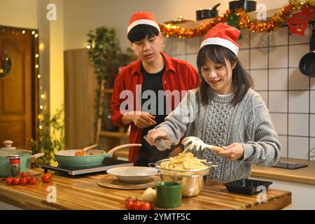 Wunderschönes junges Paar, das am Weihnachtsabend in der Küche Abendessen zubereitete Stockfoto