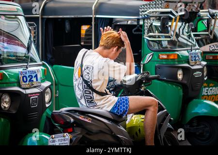 Ein gutaussehender junger philippinischer Junge schaut sich die Haare im Spiegel, der auf seinem Motorrad in der China Town Gegend von Manila auf den Philippinen sitzt. Stockfoto