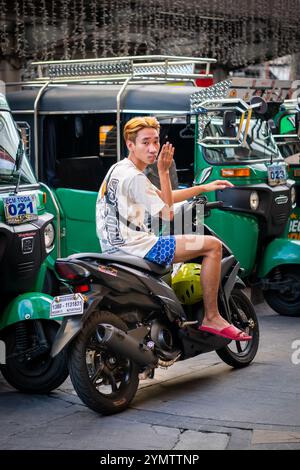 Ein gutaussehender junger philippinischer Junge schaut sich die Haare im Spiegel, der auf seinem Motorrad in der China Town Gegend von Manila auf den Philippinen sitzt. Stockfoto