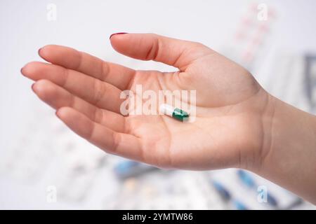 Nahaufnahme der weiblichen Hand, die pharmazeutische Pille oder Kapsel hält, bunte Medizin Pillen im Hintergrund. Stockfoto