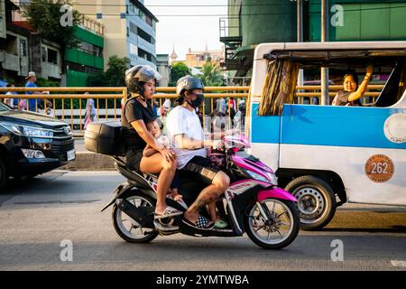 Eine junge philippinische Familie reist mit einem Motorrad durch die geschäftigen Straßen der China Town Gegend von Manila. Die Philippinen. Stockfoto