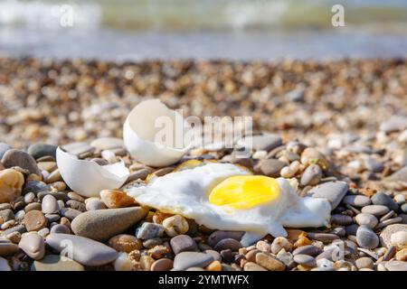 Ein Hühnerei wurde im Sand gebraten. Heißes Wetter am Strand. Stockfoto