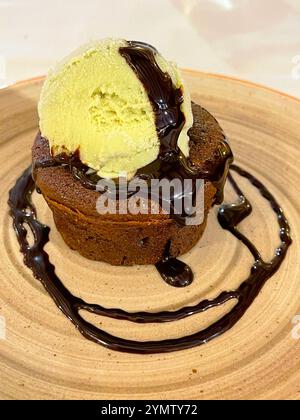 Schokoladenkuchen mit Pistcahio-Eis und Schokoladensirup. Stockfoto