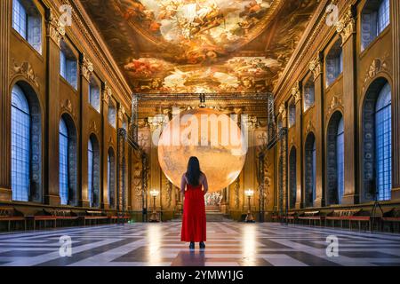 London, Großbritannien. November 2024. Das Personal posiert mit der Installation. Das Old Royal Naval College begrüßt Luke Jerrams beliebte beleuchtete Installation „Mars“ in der historischen Painted Hall. Die Installation wird ab heute bis zum 20. Januar 2025 ausgestellt. Quelle: Imageplotter/Alamy Live News Stockfoto