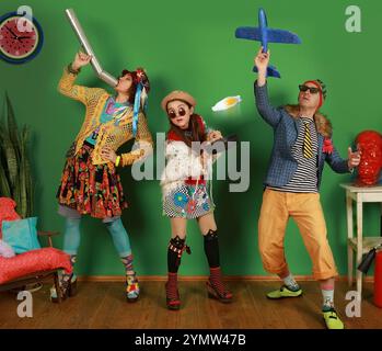 Freaks Familie hat Spaß im Studio und wirft Rührei und ein Spielzeugflugzeug auf grünem Hintergrund vor die Kamera Stockfoto
