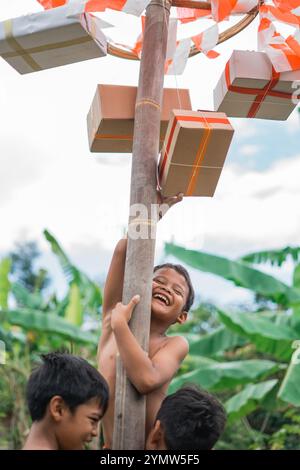 Glückliche Kinder, die Preise beim Klettern der Areca-Nuss mit Freunden zum Gedenken an Indonesiens Unabhängigkeitstag halten Stockfoto