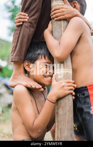 Kinder tragen das Gewicht von Freunden, die auf ihren Schultern klettern, während eines Wettkampfs zum Areca-Nuss-Klettern, um die Unabhängigkeit zu feiern Stockfoto