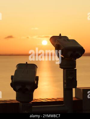 Fernglas auf der Terrasse der Abtei Tihany. Ein fantastischer Sonnenaufgang im Hintergrund, mit der Sonne eine goldene Linie über den Balaton. Stockfoto