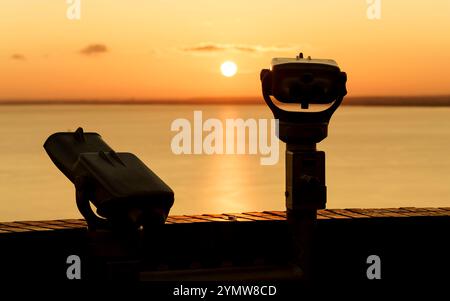 Fernglas auf der Terrasse der Abtei Tihany. Ein fantastischer Sonnenaufgang im Hintergrund, mit der Sonne eine goldene Linie über den Balaton. Stockfoto