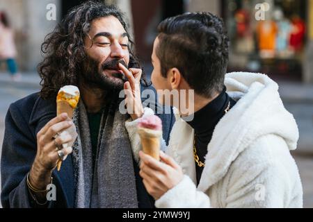 Schwule Paare teilen sich Eiskegel und Zuneigung auf der Stadtstraße Stockfoto