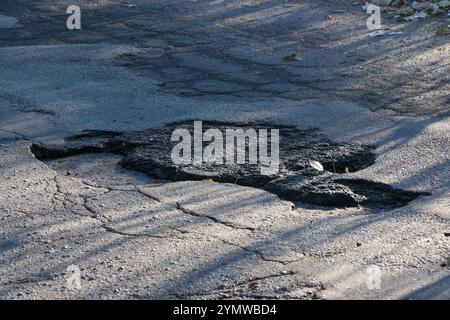 Dieses Bild zeigt einen Abschnitt einer Straße mit einem Asphaltstreifen, der durch sichtbare Risse auf der Oberfläche gekennzeichnet ist, was die anhaltenden Herausforderungen bei der Straßeninstandhaltung verdeutlicht Stockfoto