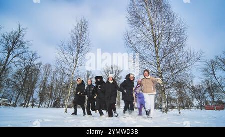 Fröhliche Schulmädchen genießen den Winter, laufen durch den verschneiten Park, tragen warme Kleidung und schaffen gemeinsam freudige Erinnerungen Stockfoto