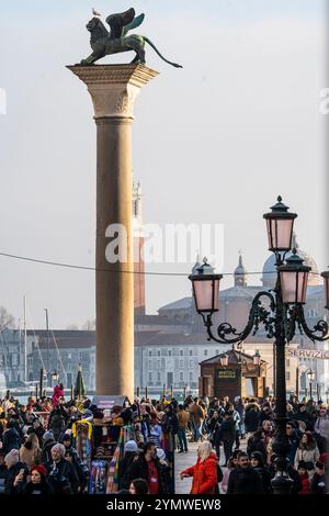 Viele Touristen rund um den Löwen von Venedig, eine alte Bronze geflügelte Löwenskulptur auf der Piazza San Marco von Venedig, Italien 04.01.2024 Stockfoto