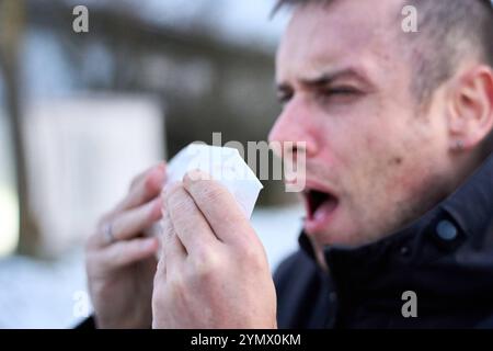 Bayern, Deutschland - 22. November 2024: Ein Mann niest draußen in ein Taschentuch. Symbolbild bei Erkältungen, Grippe und Wintergesundheitsproblemen *** ein Mann niest im Freien in einem Taschentuch. Symbolbild für Erkältung, Grippe und winterliche Gesundheitsprobleme Stockfoto