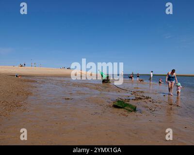 Grüne Steuerbord-Handbouy mit Touristen und Besuchern am Wells Beach am Ufer des Wassers in Richtung Hafen, Norfolk, England, Großbritannien Stockfoto