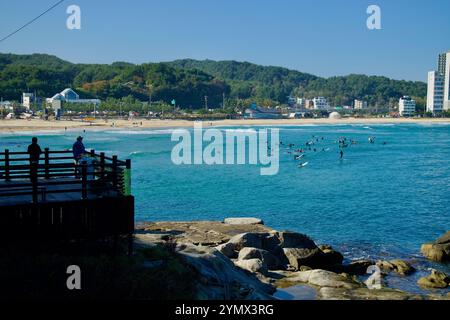 Yangyang County, Südkorea - 3. November 2024: Besucher genießen die Aussicht von einer Aussichtsplattform mit Blick auf Surfer, die auf den Wellen von Jukdo Beac reiten Stockfoto