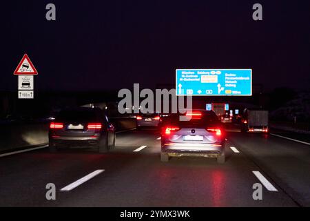 Autobahn A8, Bayern, Deutschland - 22. November 2024: Nachtverkehr auf der Autobahn A8 mit beleuchteten Rücklichtern, Verkehrsschildern und Wegweisern Richtung München und Salzburg *** Nachtverkehr auf der Autobahn A8 mit leuchtenden Rücklichtern, Verkehrsschildern und Wegweisern Richtung München und Salzburg Stockfoto