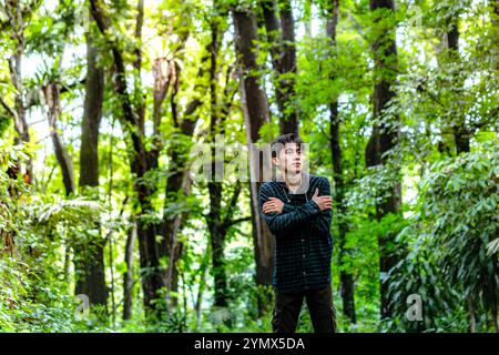 Ein Mann, der allein durch den tiefen Wald geht und Angst hat. Der Mensch fühlt sich nervös, allein im Wald zu gehen Stockfoto