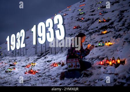 Kiew, Ukraine. November 2024. Person, die eine Kerze auf einem Hügel mit brennenden Kerzen am Holodomor Opfer Gedenktag am Holodomor Opfer Gedenktag zündet. Die großen Buchstaben 1932 bis 1933 symbolisieren die Zeit des Holodomors. Während des Holodomors verhungerten Millionen Ukrainer aufgrund einer von Menschen verursachten Hungersnot. Jeden 4. Samstag im November um 4 Uhr werden die Kerzen in der ganzen Ukraine gezündet. Quelle: Andreas Stroh/Alamy Live News Stockfoto