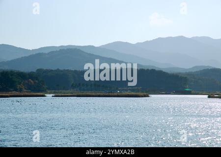 Yangyang County, Südkorea - 3. November 2024: Das sonnendurchflutete Wasser des Pomae Lake glitzert vor dem Hintergrund von übereinander bewaldeten Hügeln und weit entfernten Mo Stockfoto