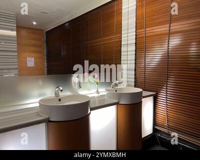 Sauberes, neues öffentliches Badezimmer mit weißem Waschbecken und Armaturen. Öffentliche Toiletten innen. Stockfoto