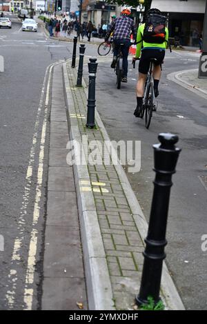 Zwei Radfahrer, die im Stadtzentrum von Bristol einen eigenen Radweg nutzen, der durch Schiffspoller und Betonsteinkante von der Straße getrennt ist Stockfoto